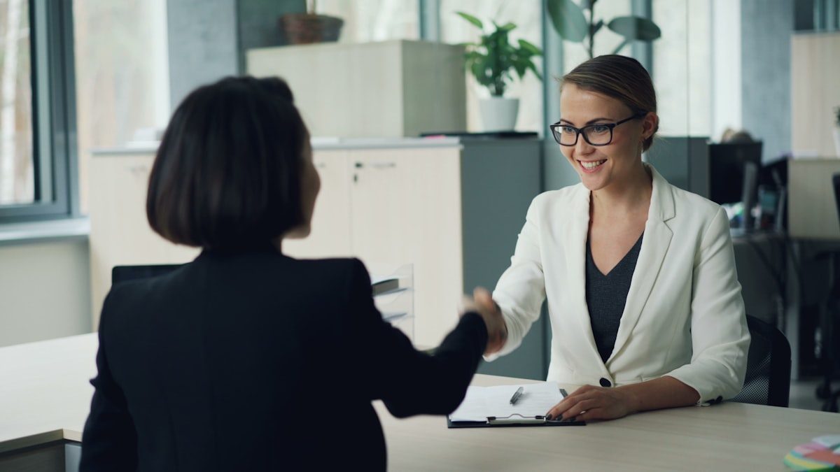 Deux femmes se serrant la main par-dessus un bureau lors d'un rendez-vous